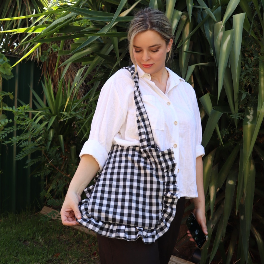 Woman modeling the ruffle tote bag made from a Mercy Makes sewing pattern.